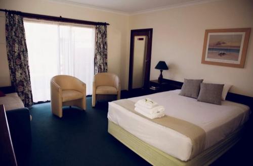 The Miners Rest Motel في كالغورلي: غرفة فندقية بسرير كبير ونافذة
