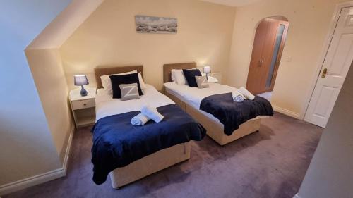 a bedroom with two beds with blue sheets at Swindon House by Cliftonvalley Apartments in Swindon