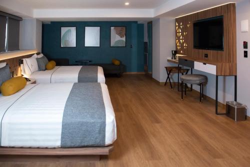 a hotel room with a large bed and a flat screen tv at Hotel Flamencos Centro Histórico in Mexico City