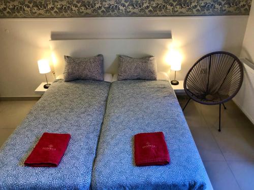 a bedroom with a blue bed with two red pillows at Mandula Apartman in Cegléd