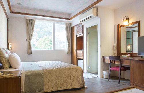 a bedroom with a bed and a desk and a window at 意大利溫泉會館 in Jiaoxi