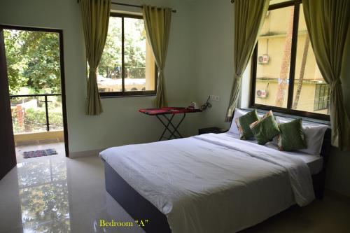a bedroom with a large bed with green pillows at Mango Apartment @ Palolem Garden Estate in Canacona