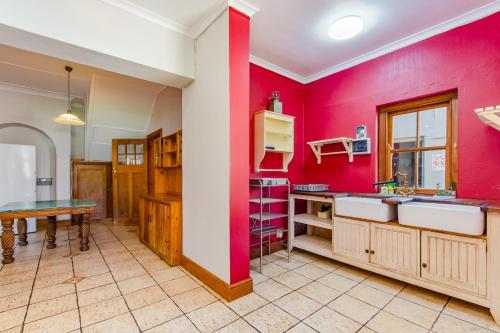 a kitchen with red walls and a table in it at Kana guest farm - 35 rooms for 70 guests in Stellenbosch