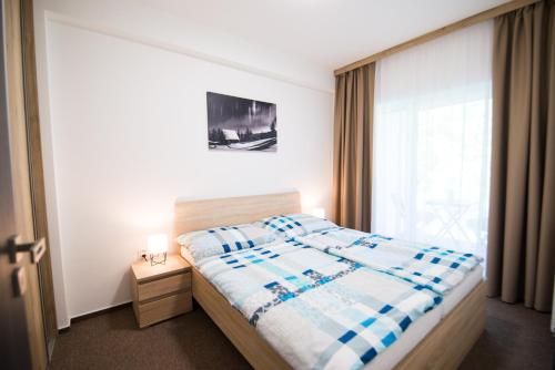 Un dormitorio con una cama y una ventana grande. en Galeria Apartments, en Demänovská Dolina