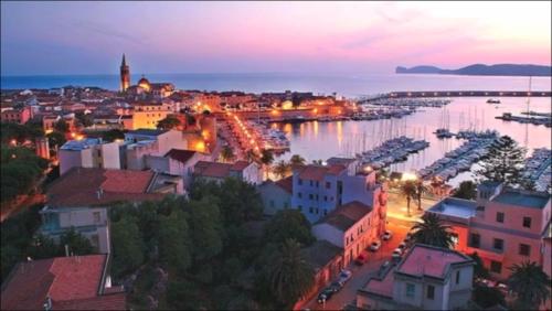a city at night with a harbor and boats at Casa Vacanze San Michele in Alghero