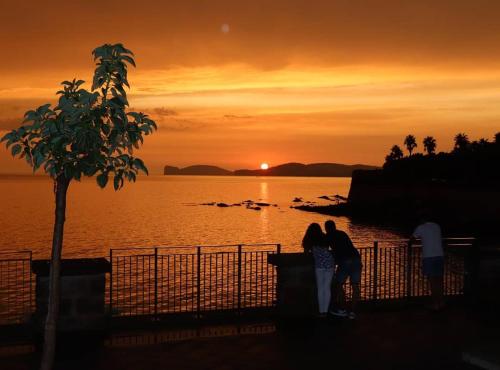 two people standing next to a fence watching the sunset at Casa Vacanze San Michele in Alghero