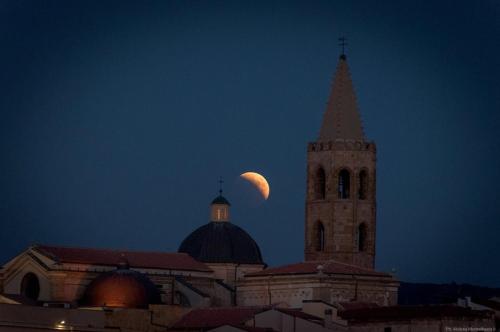 a moon over a building with a tower and a church at Casa Vacanze San Michele in Alghero
