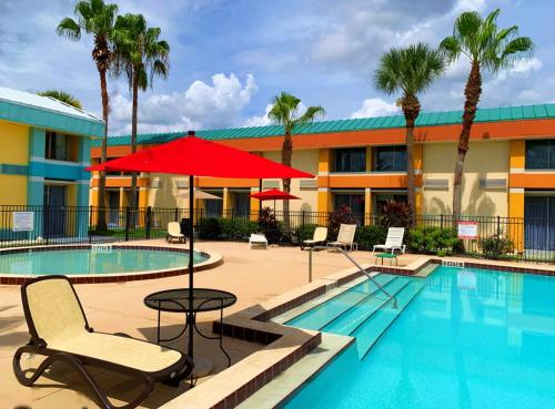 a pool with a red umbrella and chairs and a hotel at Bposhtels Orlando Florida Mall in Orlando