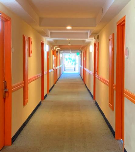 a corridor in an empty building with orange doors at Bposhtels Orlando Florida Mall in Orlando