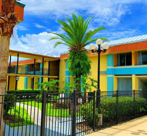 a building with a fence and a palm tree at Bposhtels Orlando Florida Mall in Orlando