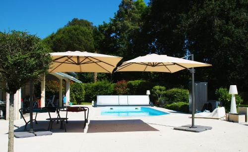 twee parasols en een tafel en stoelen naast een zwembad bij Ursuslodge in Soustons