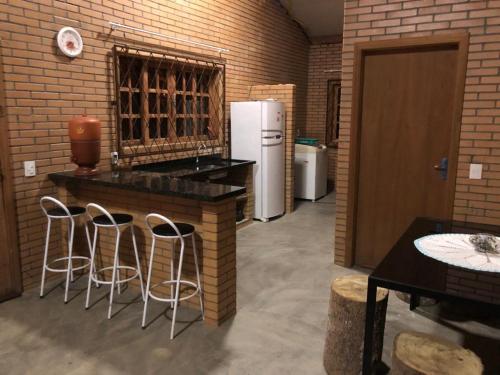 La cuisine est équipée d'un comptoir avec tabourets et d'un réfrigérateur. dans l'établissement Casa de Campo - Chácara - Lagoa dos Encantos, à Barra Velha