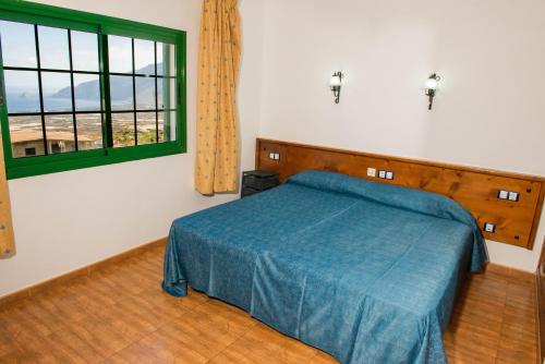 a bedroom with a blue bed and a window at Apartamentos la Palmera in Frontera