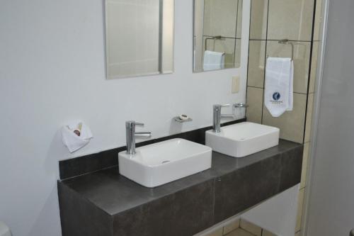 a bathroom with two sinks and mirrors on a counter at Hotel Suites del Real in Guadalajara