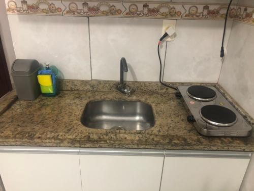 um balcão de cozinha com um lavatório e um fogão em Apartamento em Floripa -ao lado do Aeroporto e juntinho as praias do Sul da Ilha em Florianópolis