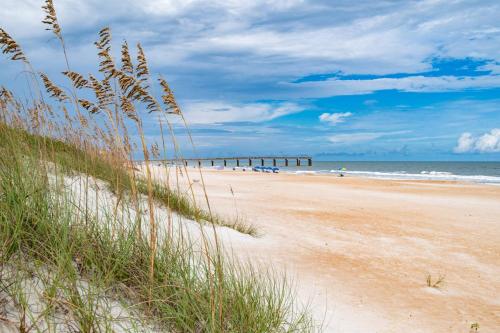 a sandy beach with a pier in the ocean at Golden Mile Beach Retreat in St. Augustine