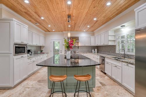 a kitchen with white cabinets and a large island with two stools at Golden Mile Beach Retreat in St. Augustine