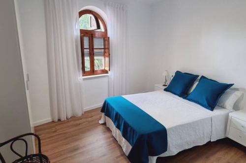 um quarto com uma cama com almofadas azuis e uma janela em Casa Pedra de Roder em Vilafamés