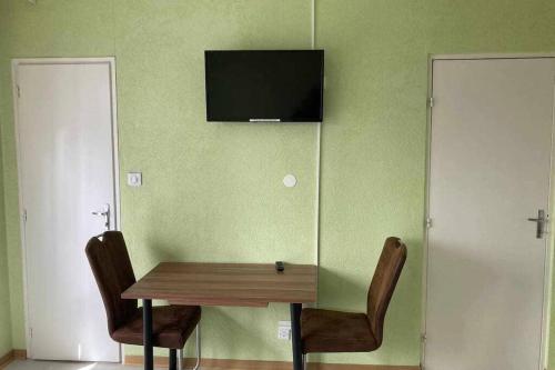 einen Tisch und zwei Stühle mit einem TV an der Wand in der Unterkunft Studio Lora RM 1184L in Saint-Louis