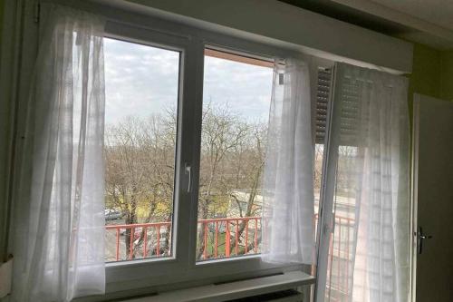 ein Fenster mit weißen Vorhängen und einem Balkon in der Unterkunft Studio Lora RM 1184L in Saint-Louis