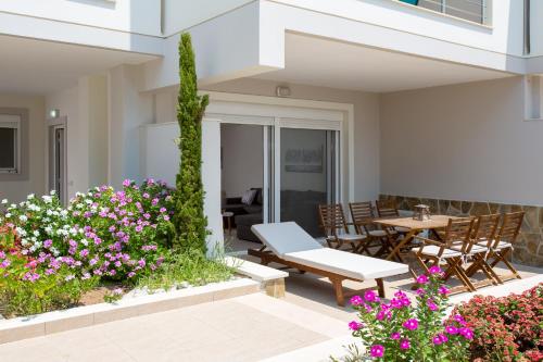 a patio with a table and chairs and flowers at Kymata Apartment Ierapetra in Ierápetra
