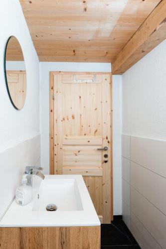 a bathroom with a white sink and a wooden door at Fohlenwies - romantische Berghütte in Alleinlage Osttirol in Lienz
