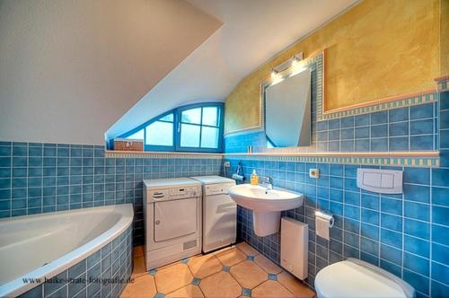 a blue tiled bathroom with a sink and a tub at Sonnenschein in Zingst