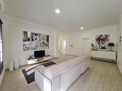 a white living room with a couch and a tv at Espírito Santo - AL in Ponta Delgada