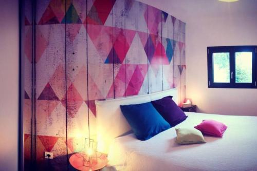 a bedroom with a bed with blue and pink pillows at Gîte de charme : A la volette in Plombières-les-Bains