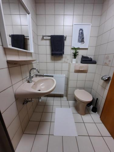 La salle de bains blanche est pourvue d'un lavabo et de toilettes. dans l'établissement Apartment Weitblick, à Butjadingen