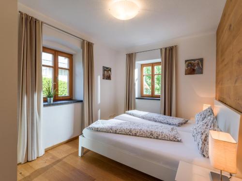 a bedroom with a bed and two windows at Villa Grete, St. Johann in Tirol in Sankt Johann in Tirol