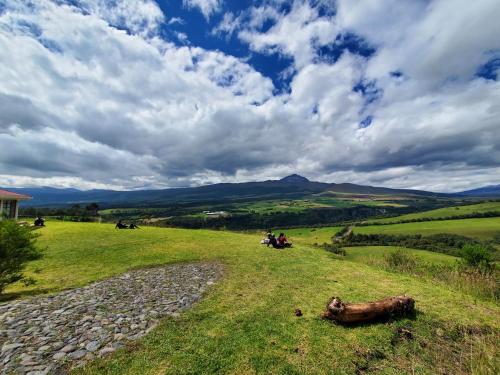 a group of people sitting on a grassy hill at Balcon al Cotopaxi Hosteria in Sangolquí
