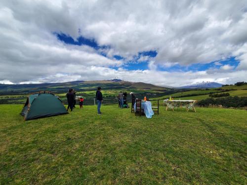 a group of people standing in a field next to a tent at Balcon al Cotopaxi Hosteria in Sangolquí