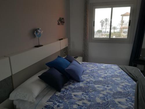 una camera da letto con un letto con cuscini blu e una finestra di Apartamento Playa de las vistas Torres del Sol C3 308 ad Arona