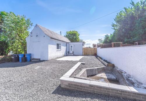 a backyard with a white building and a driveway at 1 Bed Cottage-Sleeps 2-Parking-Pets-Hot Tub in Kelty