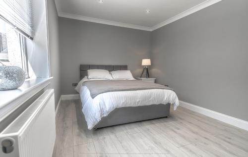 een witte slaapkamer met een bed en een raam bij Lovely 1-Bed Cottage in Kelty with Hot Tub in Kelty
