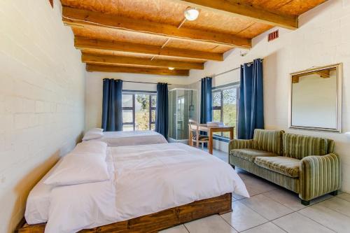 a bedroom with a large bed and a couch at Kana guest farm - 35 rooms for 70 guests in Stellenbosch