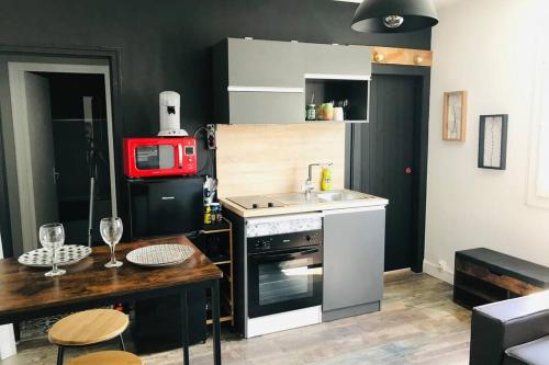une petite cuisine avec une cuisinière et un micro-ondes dans l'établissement Appartement 2/3 pers, centre ville avec parking., à Saint-Brévin-les-Pins