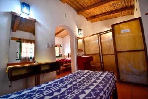 a bedroom with a bed and a desk in a room at Hosteria la granja in Huacalera