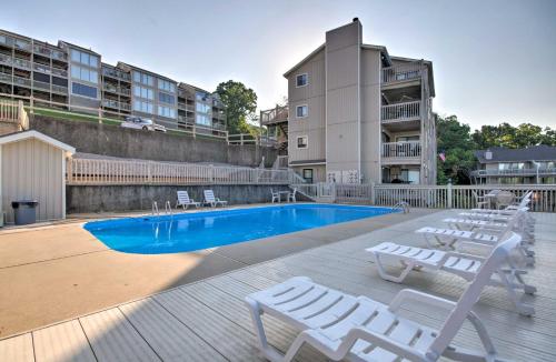a swimming pool with white lounge chairs next to a building at Community Pool Lakefront Osage Beach Condo! in Osage Beach