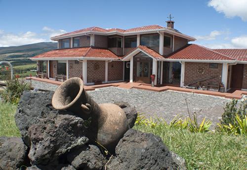 a large house with a large rocks in front of it at Balcon al Cotopaxi Hosteria in Sangolquí