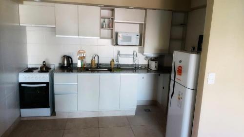 una pequeña cocina con armarios blancos y refrigerador. en ArenalesDOS49 en Salta