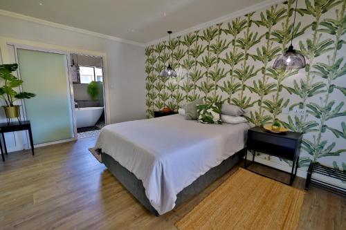Un dormitorio con una cama y una pared con plantas. en 18 Storm Sea, en Agulhas