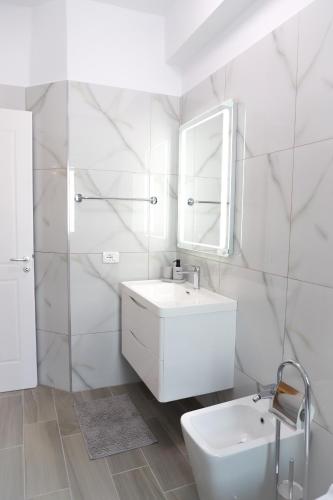 a white bathroom with a sink and a mirror at Olimpia Inn in Berat