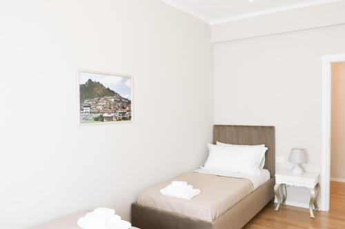 a white bedroom with a bed and a table at Olimpia Inn in Berat