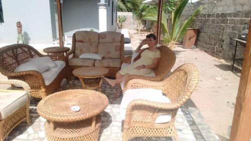 a man sitting on a chair in a patio at Remarkable 4-Bed with air conditioning in Brikama in Brikama