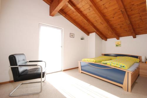 1 dormitorio con 1 cama y 1 silla en Allegria, en Gambarogno