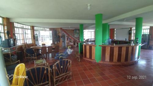Casa Redonda في Suaita: غرفة معيشة بها أعمدة خضراء وطاولات وكراسي