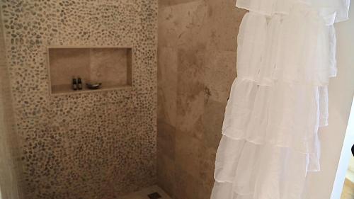 a shower with a white curtain in a bathroom at Cozy room near the beach, party zone in Tulum