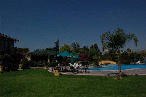a yard with a pool with a table and chairs at Gran Hotel Hacienda De La Noria in Aguascalientes